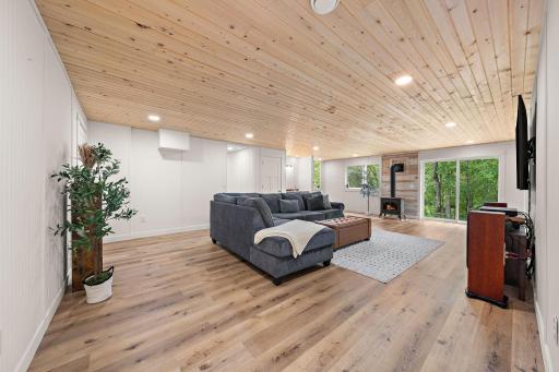 A view of the family room from the full lower level bathroom. The fifth bedroom is on the far right to the right of the patio doors and the hallway with utility room and fourth bedroom is beyond the couch.
