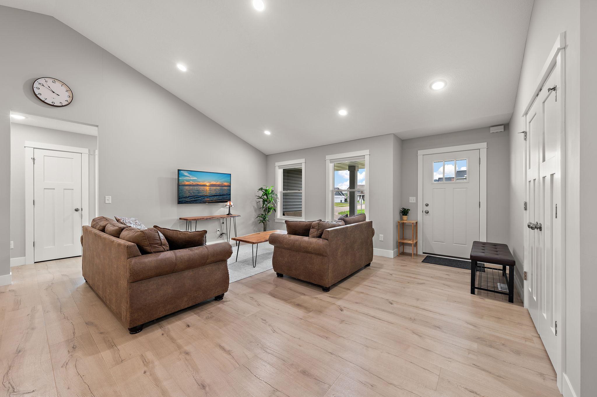 The living room has wood floors and the hallway leading to the second and third bedrooms and second bathroom is visible on the left through hallway.