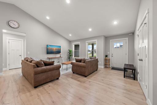 The living room has wood floors and the hallway leading to the second and third bedrooms and second bathroom is visible on the left through hallway.