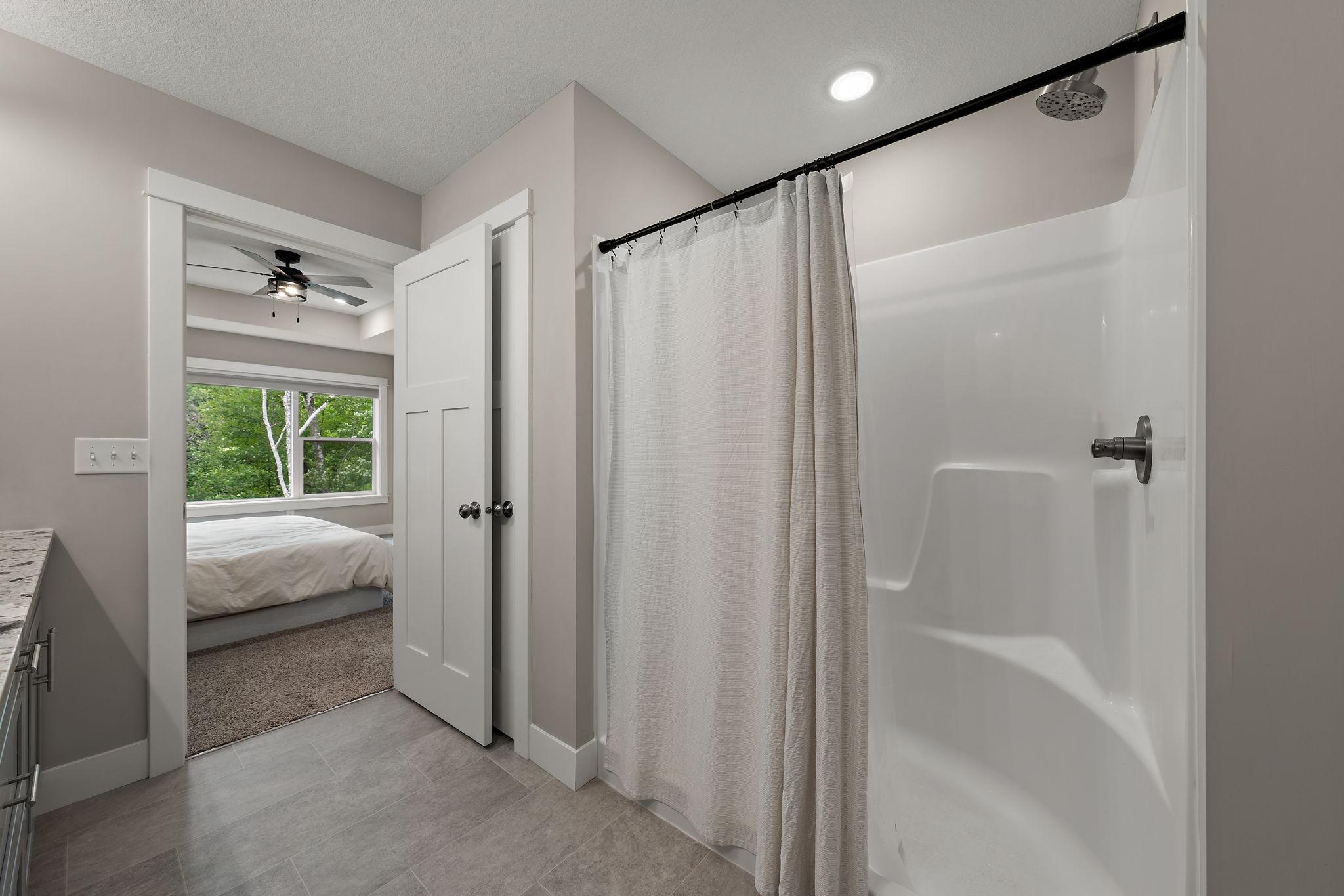 A view from the bathroom with open door to the primary bedroom beyond. The primary ensuite bathroom has a walk-in shower.