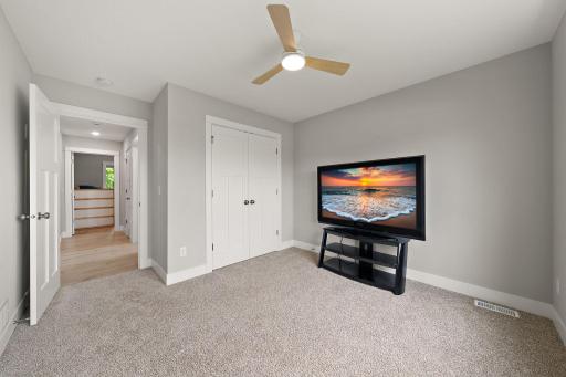 The second bedroom with open hallway door on the left with third bedroom visible across the hallway and clothes closets on the far right.