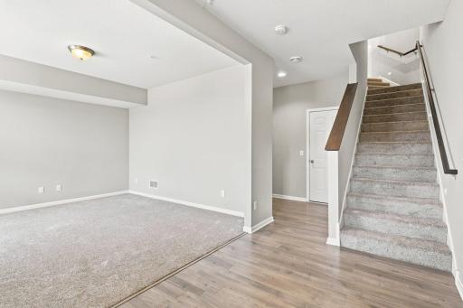 5140 Hampton St NE - Foyer opens to the family room and stairs to the main level. The door in the back offers access to the garage, and to the left behind the family room is found a coat closet and a half bath.