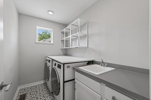 Upper level laundry room complete with storage shelves and a laundry sink!