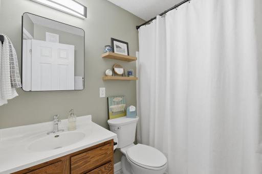 Bath has a tub and shower, updated mirror and lighting.