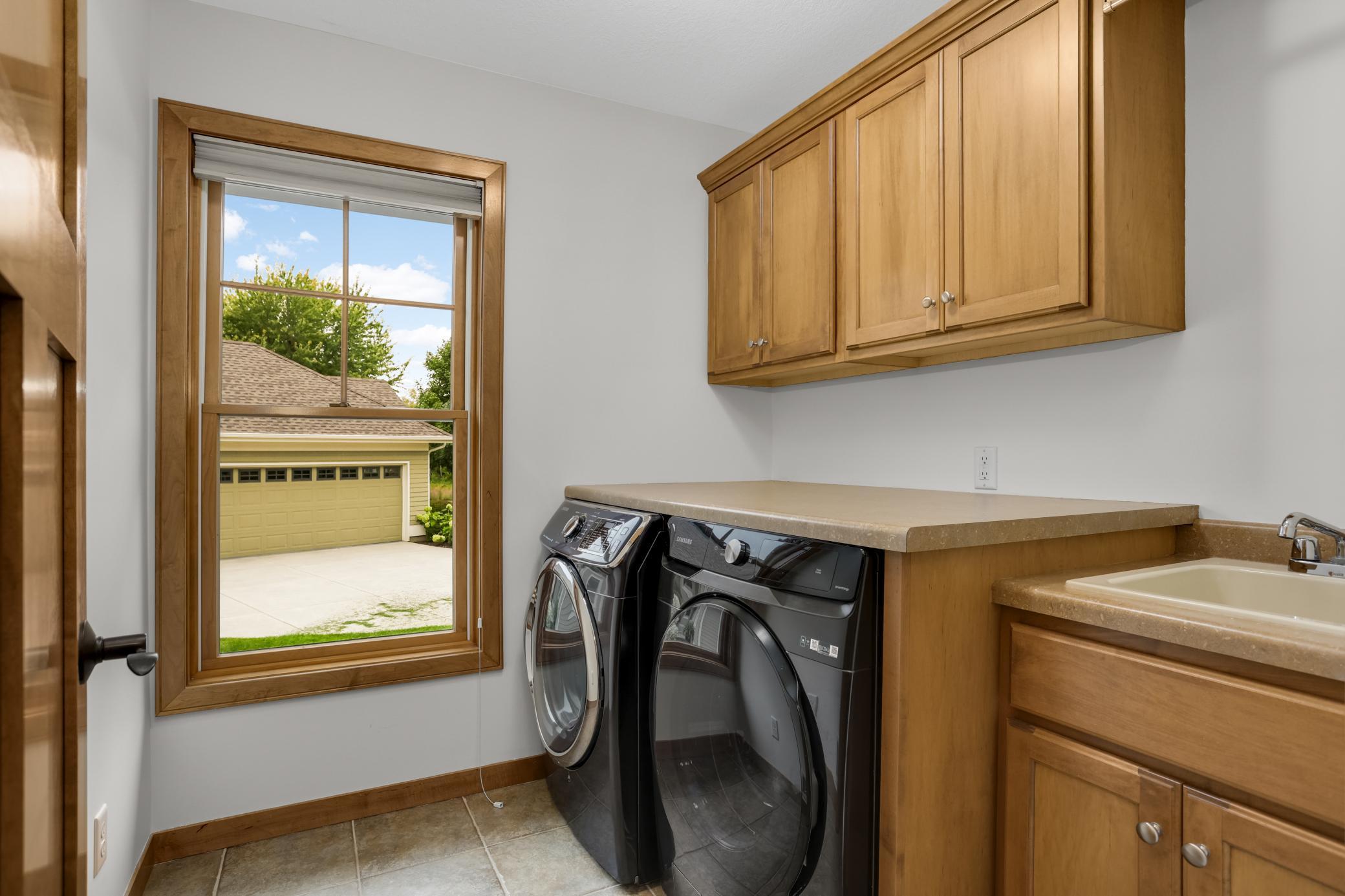 Main-level laundry with custom cabinetry with beautiful real-wood shelving for added storage and organization.