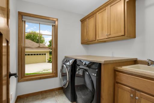 Main-level laundry with custom cabinetry with beautiful real-wood shelving for added storage and organization.