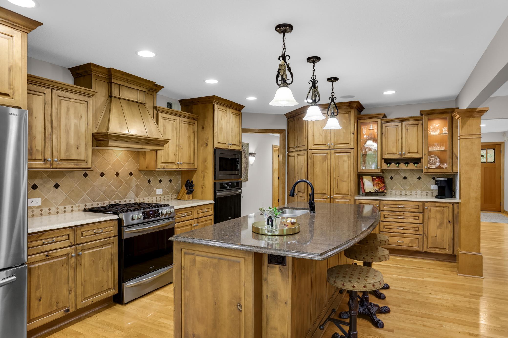 Neutral tile backsplash, convenient coffee bar, dual ovens, and abundant knotty alder cabinetry that adds warmth and character.