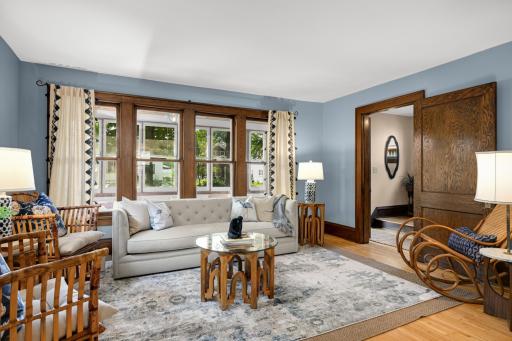 Open sun-filled living room with refinished maple floors and rich oak trim.