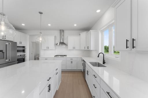 (Photo of a similar home, actual finishes may vary) The focal point of this modern kitchen is an inviting center island that provides additional counter and seating space. It is surrounded by ample cabinetry and all-new stainless steel appliances.