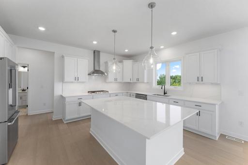 (Photo of a similar home, actual finishes may vary) The center island has pull-up seating to entertain guests while cooking