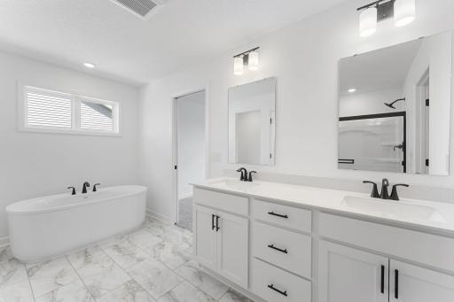 (Photo of a similar home, actual finishes may vary) Featuring a sophisticated dual-sink vanity with separate mirrors, this en-suite bathroom ensures streamlined morning routines