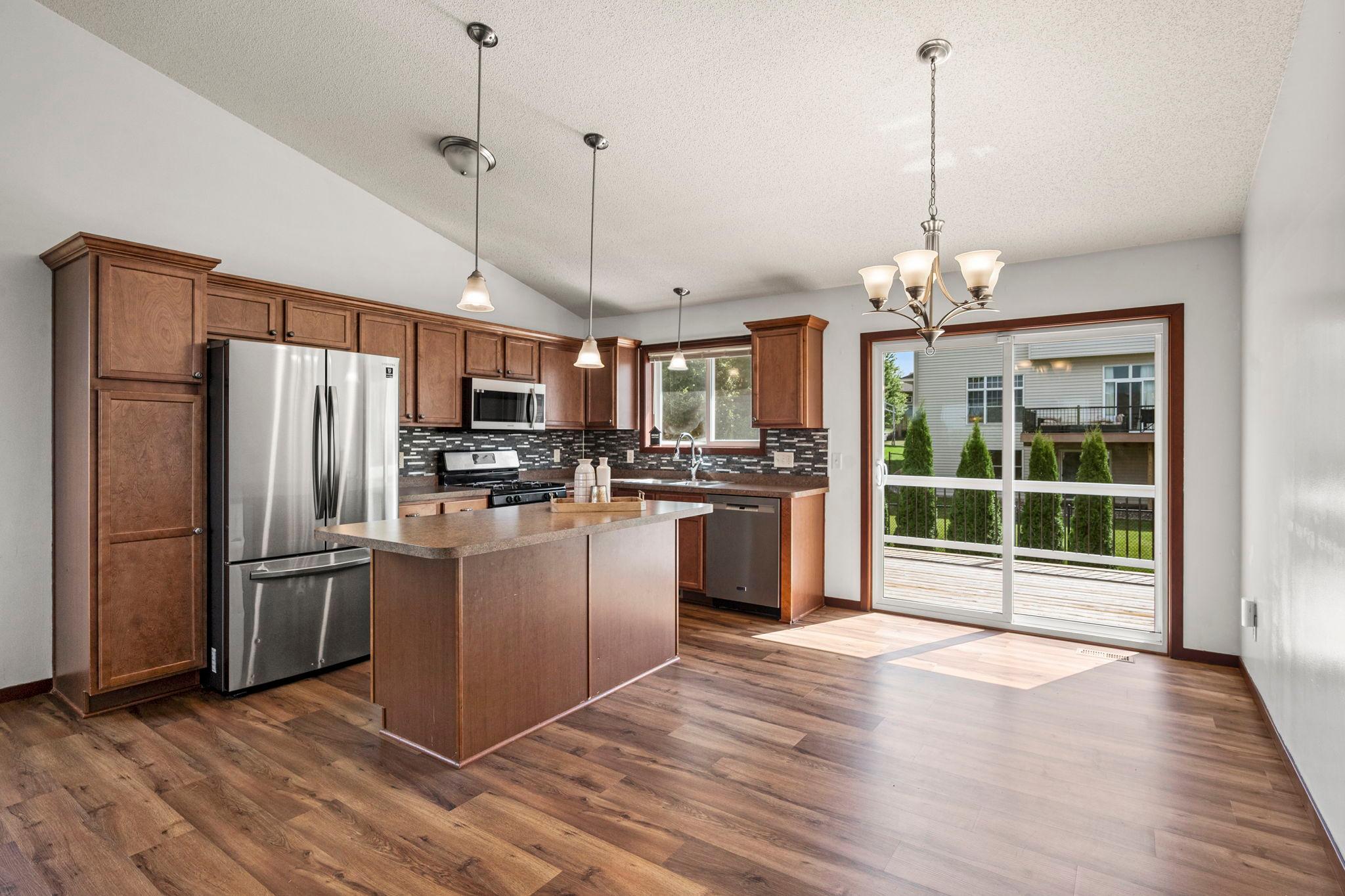The open floor plan kitchen features a large center island and stainless steel appliances. High quality LVP flooring has been installed throughout the home.