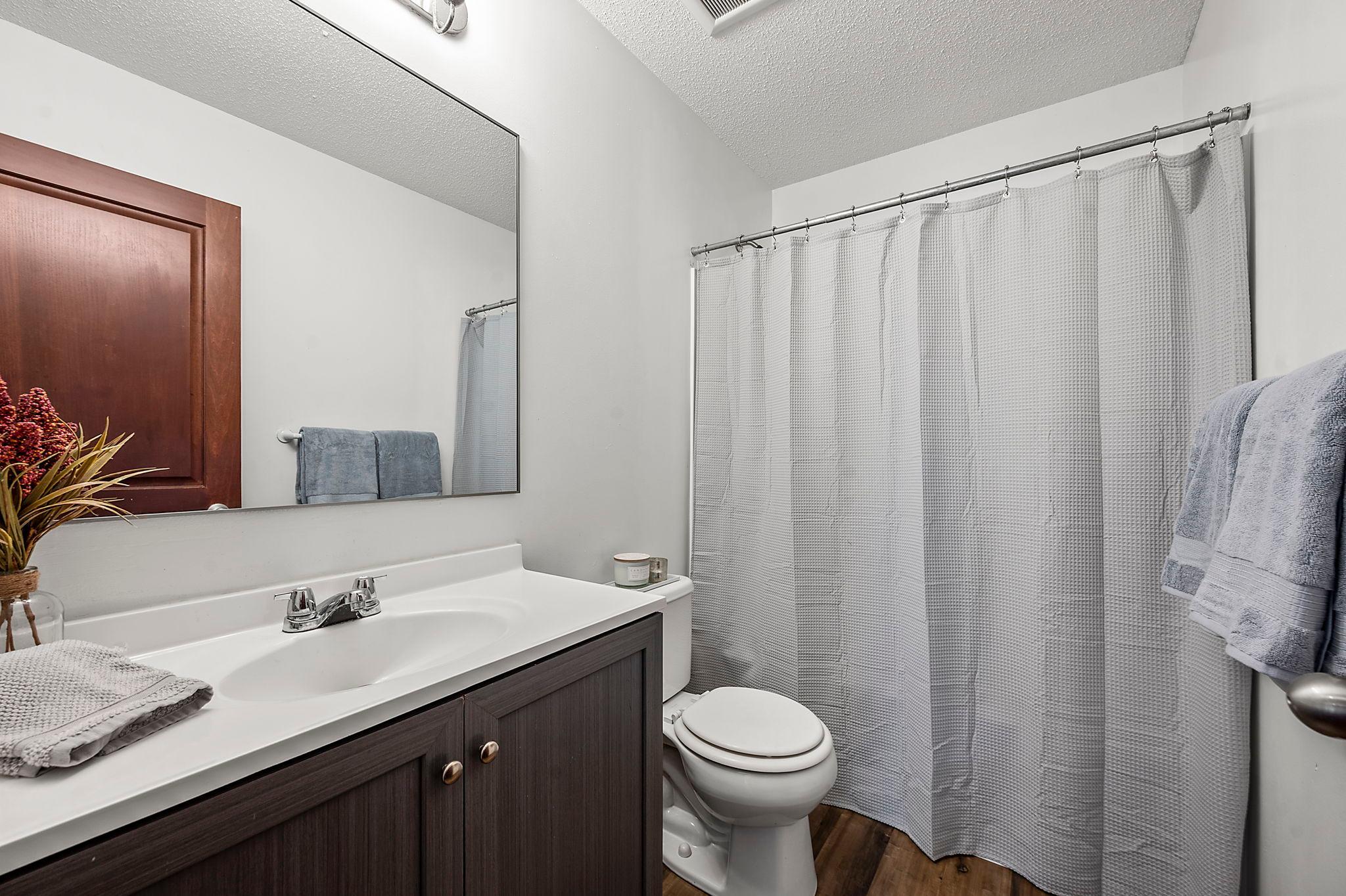 The main floor full bath has been updated with a new vanity, sink, mirror, flooring and shower enclosure.