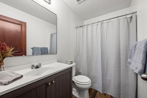 The main floor full bath has been updated with a new vanity, sink, mirror, flooring and shower enclosure.