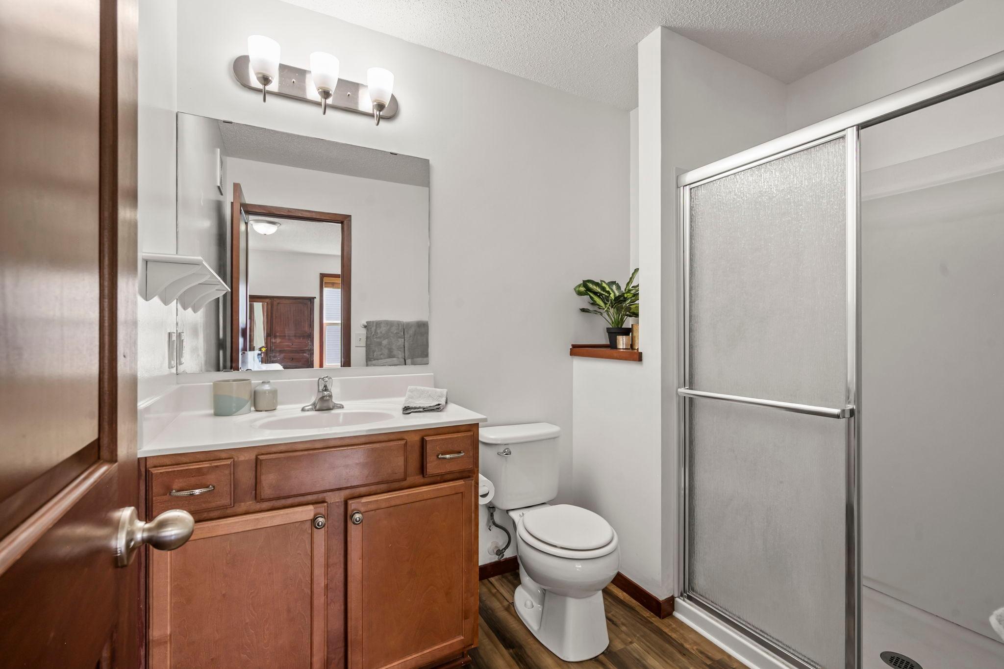 Primary bedroom bathroom has been updated with a new shower enclosure and new flooring.
