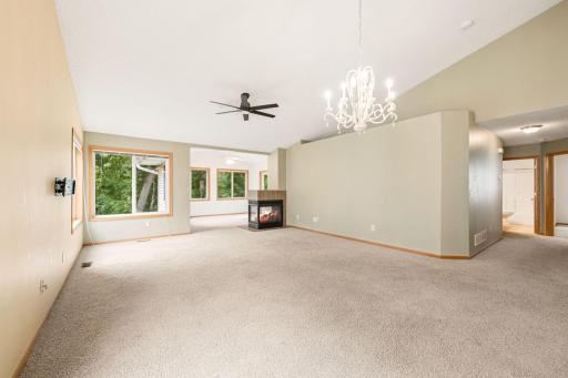 Open living room facing sunroom with 3-sided fireplace