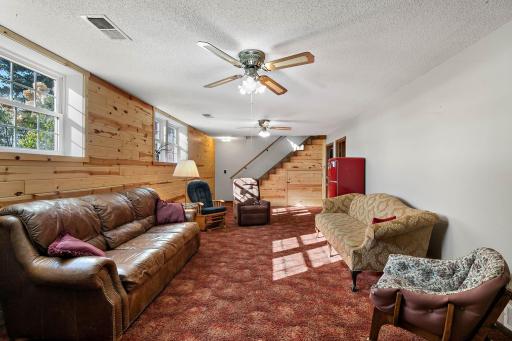 Beautiful knotty pine accent wall and stairs - also appreciate the large bright windows - this does not feel like a lower level room!