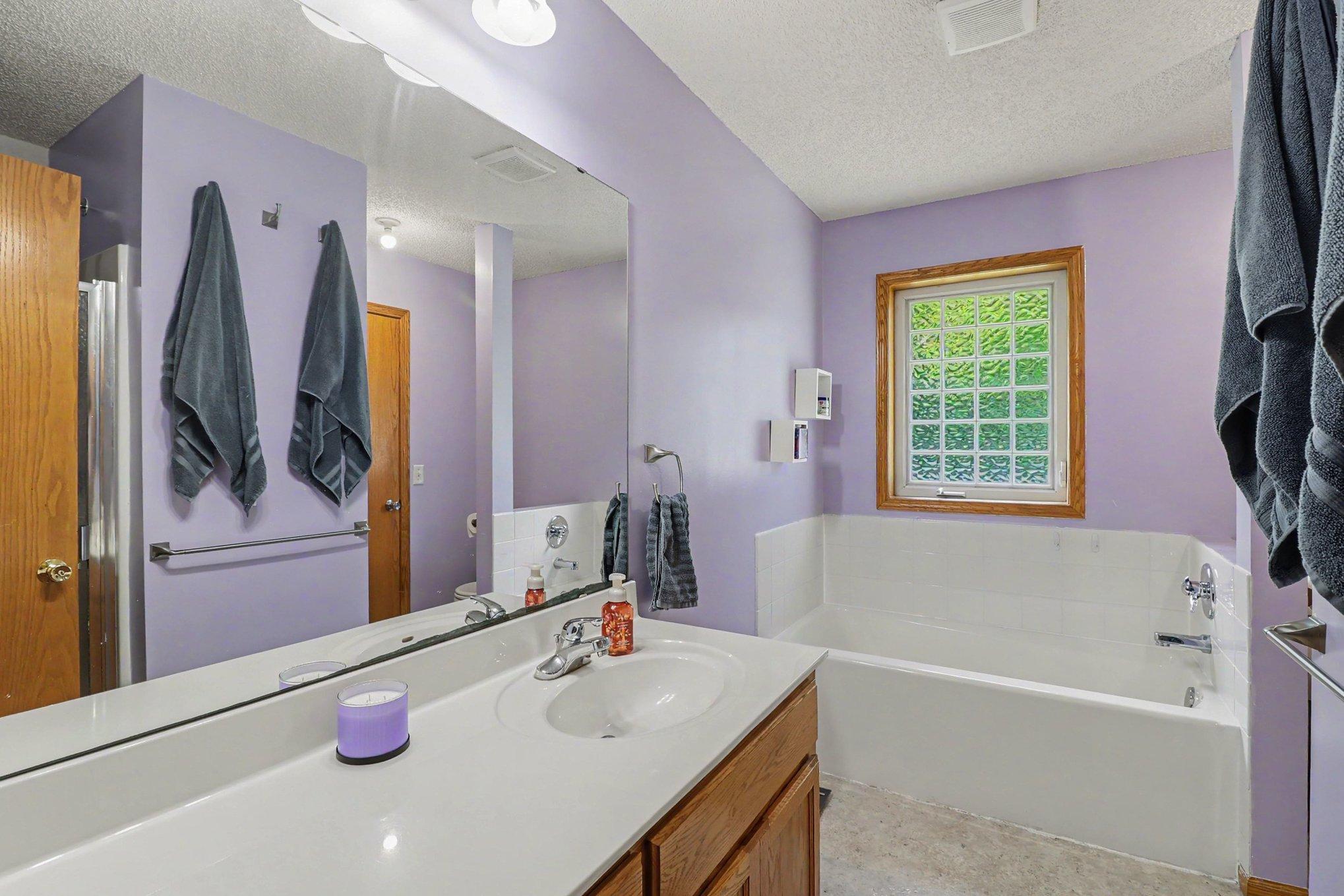 Main-level full bath with a separate tub and shower, accessible from the primary bedroom and hall.