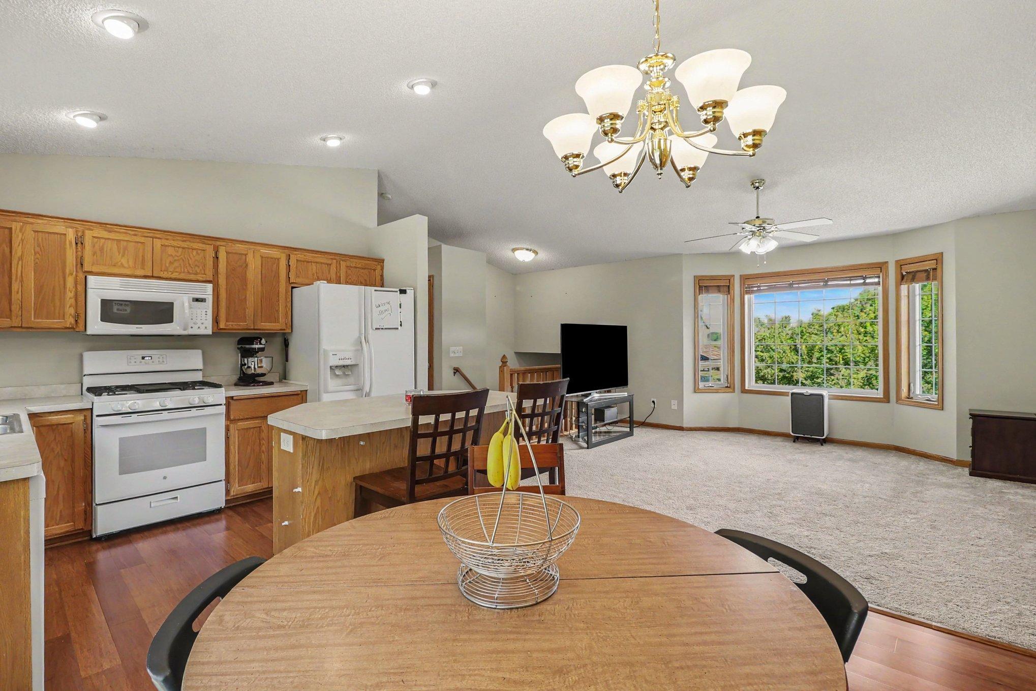 Open dining and kitchen area with island seating and vaulted ceiling.