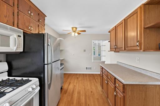 A view of the eat in kitchen with hardwood floors and another ceiling fan to cool things off in the Spring.