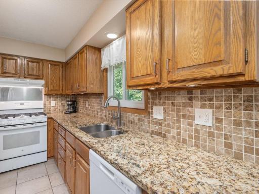 The kitchen features granite countertops, tile flooring & tile backsplash.