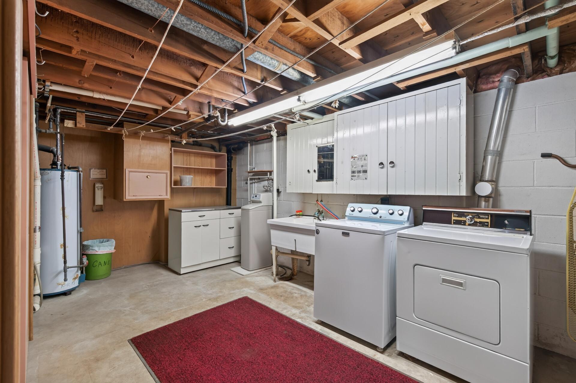 Huge laundry, mechanical room with double laundry tub, cabinets and storage.