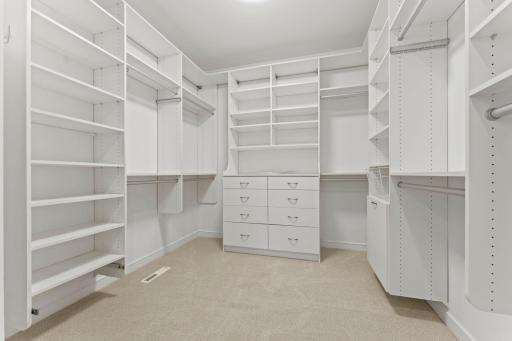 Huge primary suite walk-in closet with custom organizers and two convenient entrances.