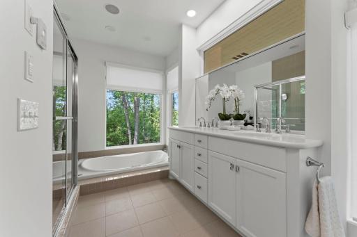 Primary suite spa-like bath with heated floor tiles, walk-in shower, comfort height double vanity, huge sunken jetted tub, walls of glass, and power blinds.