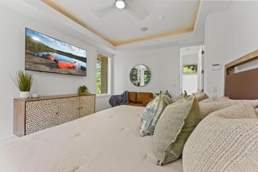 Main floor primary suite features warm soffit lighting, new ceiling fan, new carpet, new LED TV, and more!