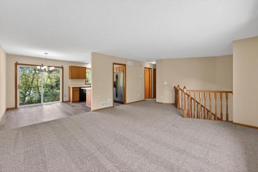 Spacious upper-level living room with abundant natural light, neutral finishes, and an open layout connecting to the dining and kitchen areas.