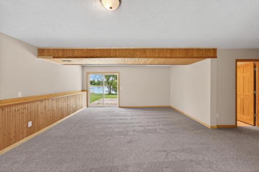 Comfortable lower-level living area with rustic wood detailing, oversized gathering space, and peaceful views overlooking the water and backyard.
