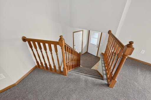 Welcoming split-entry foyer with oak railings, neutral finishes, and easy access to both upper and lower living spaces.