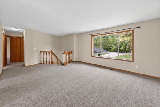 Bright and inviting living area featuring updated carpeting, large picture window, and plenty of space for relaxing or entertaining.