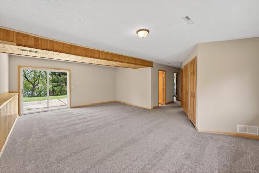 Expansive lower-level family room featuring updated carpeting, warm wood accents, and walkout sliding glass door access to the backyard and water views.