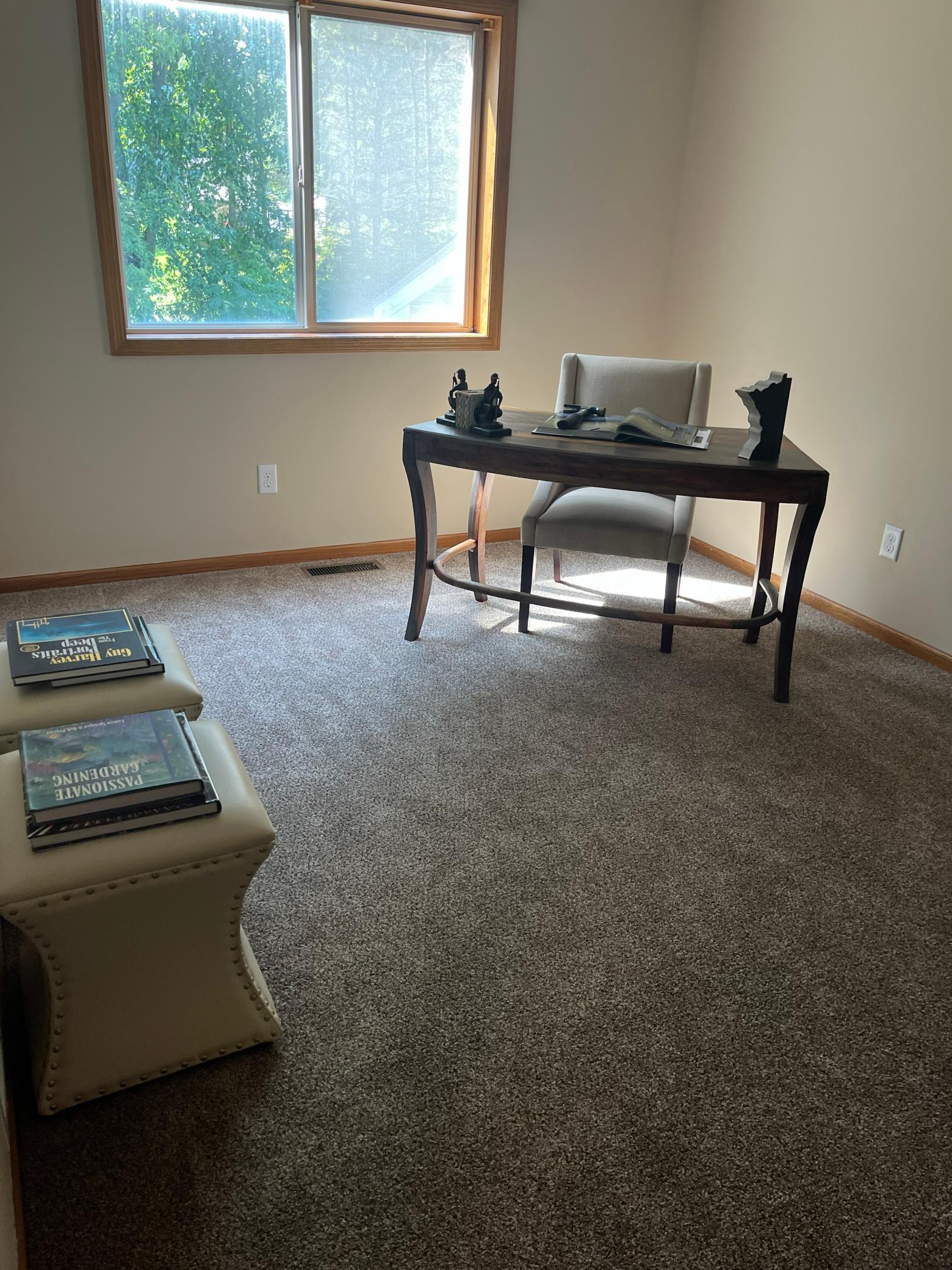 Second upper-level bedroom featuring updated carpeting, neutral finishes, and a large window with peaceful views.