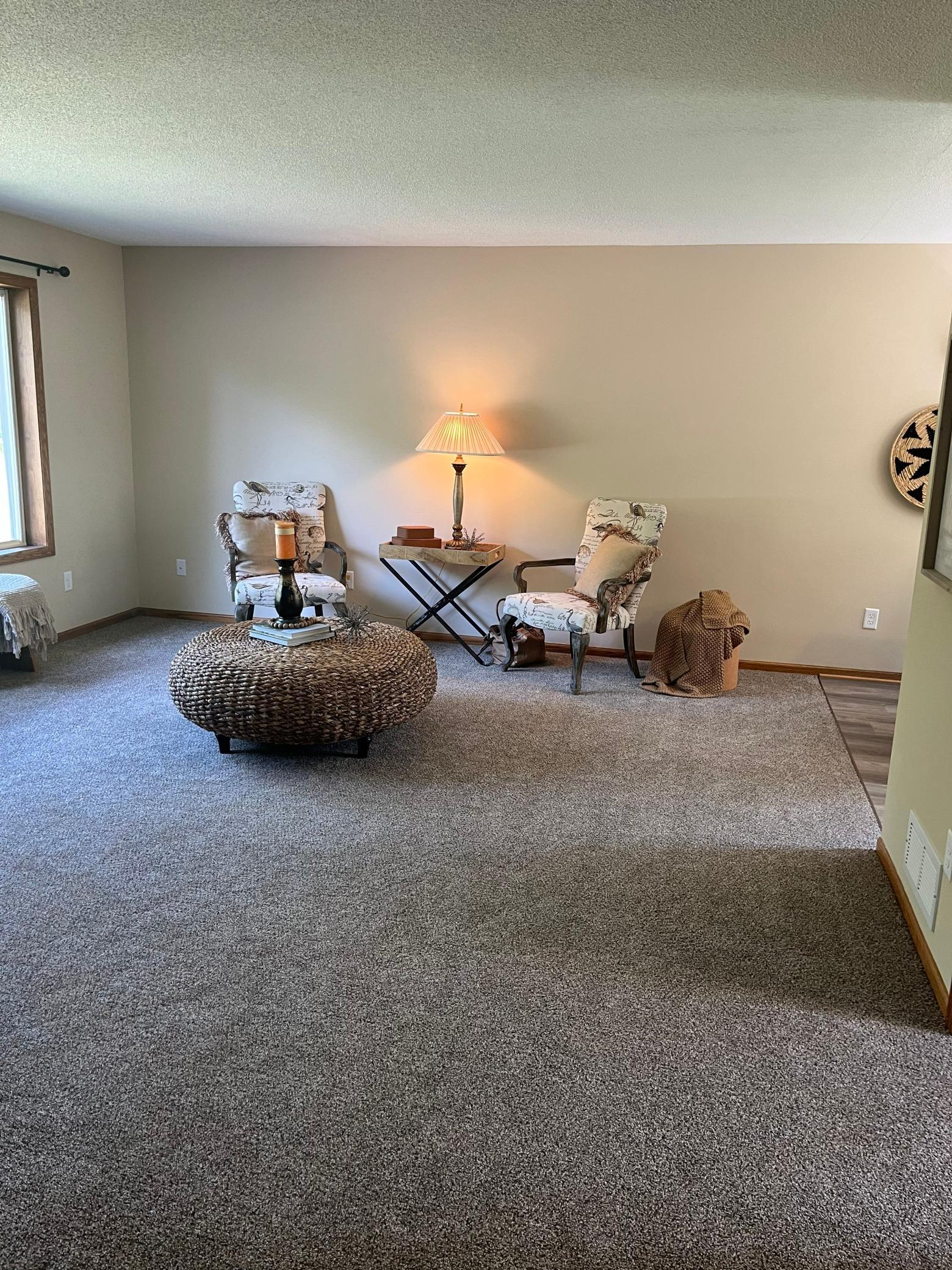 Bright and inviting living area featuring updated carpeting, large picture window, and plenty of space for relaxing or entertaining.