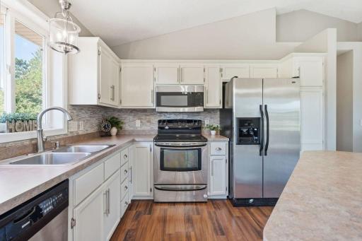 The spacious kitchen offers plenty of counter space and cabinetry for all your cooking needs, complemented by attractive laminate wood floors, an electric stove, and a sleek stainless-steel side-by-side refrigerator.