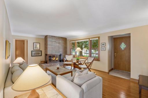 Welcoming front living room with entry coat closet, charming fireplace, large picture window, cove ceilings and original wood floors!