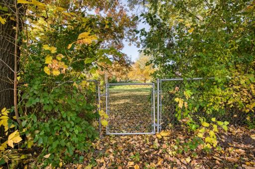Fully fenced yard with gate to enter Mud Lake Park