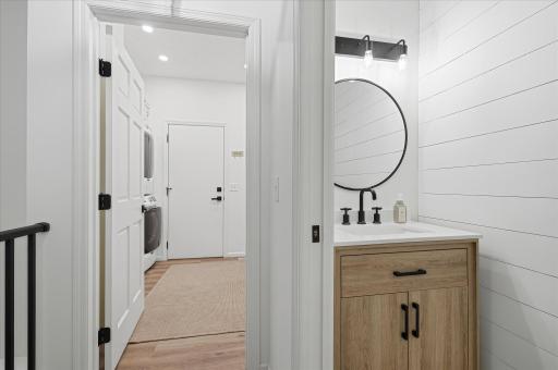 There is a 1/2 bath with a shiplap wall, a pocket door, modern black fixtures and a quartz top vanity cabinet.