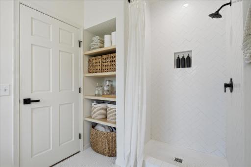 There's that four shelf storage system, right next to that stunning tile surround shower. The tile goes all the way to the ceiling!