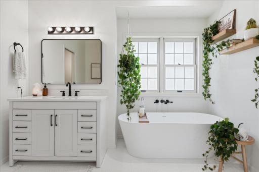 The private primary bath features tile floors, an Akdy soaking tub, a quartz-top vanity cabinet and modern fixtures. The floating shelves are included too!
