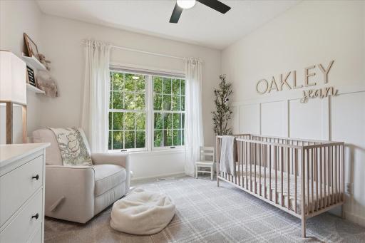 This is the rear bedroom on the opposite side of the home from the primary suite. It features cordless room-darkening honeycomb shades, a ceiling fan w/separate light & fan switches, and a board & batten feature wall.