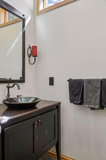 The main level 1/2 bath is tucked away in the private mudroom area. Quartz countertop with a hand-blown sink.