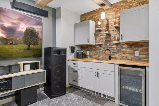 Wet bar with slate backsplash, butcher block countertop, baseboard heat, built-in fridge.