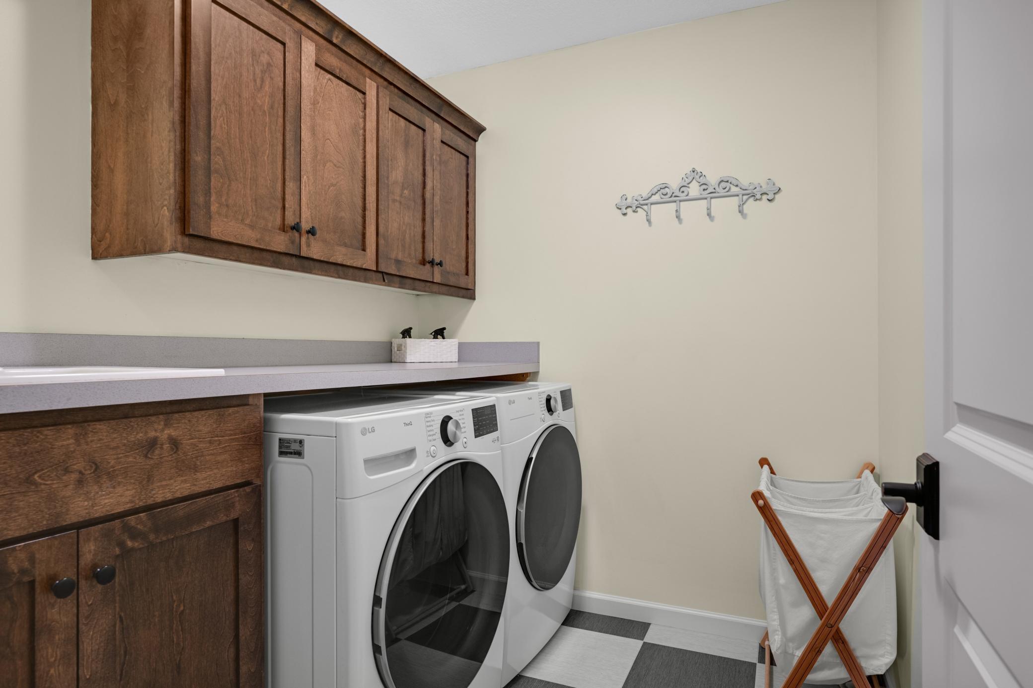 The upper-level laundry features a newer washer and dryer, incredible storage, a utility sink, and plenty of counter space for folding laundry.