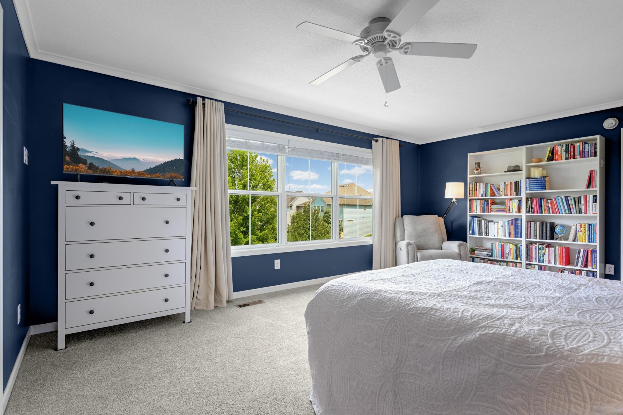 The spacious primary bedroom overlooks the gorgeous green backyard.