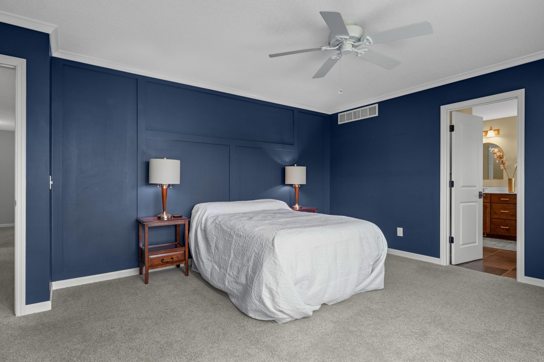 The beautiful rich navy blue paint and accent wall in the primary bedroom is perfectly on trend.