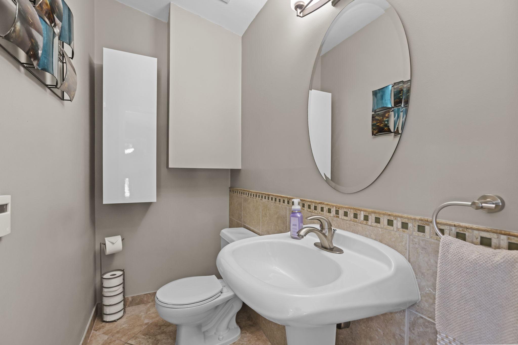 Half bathroom has a heated tile floor, tiled wall, pedestal sink