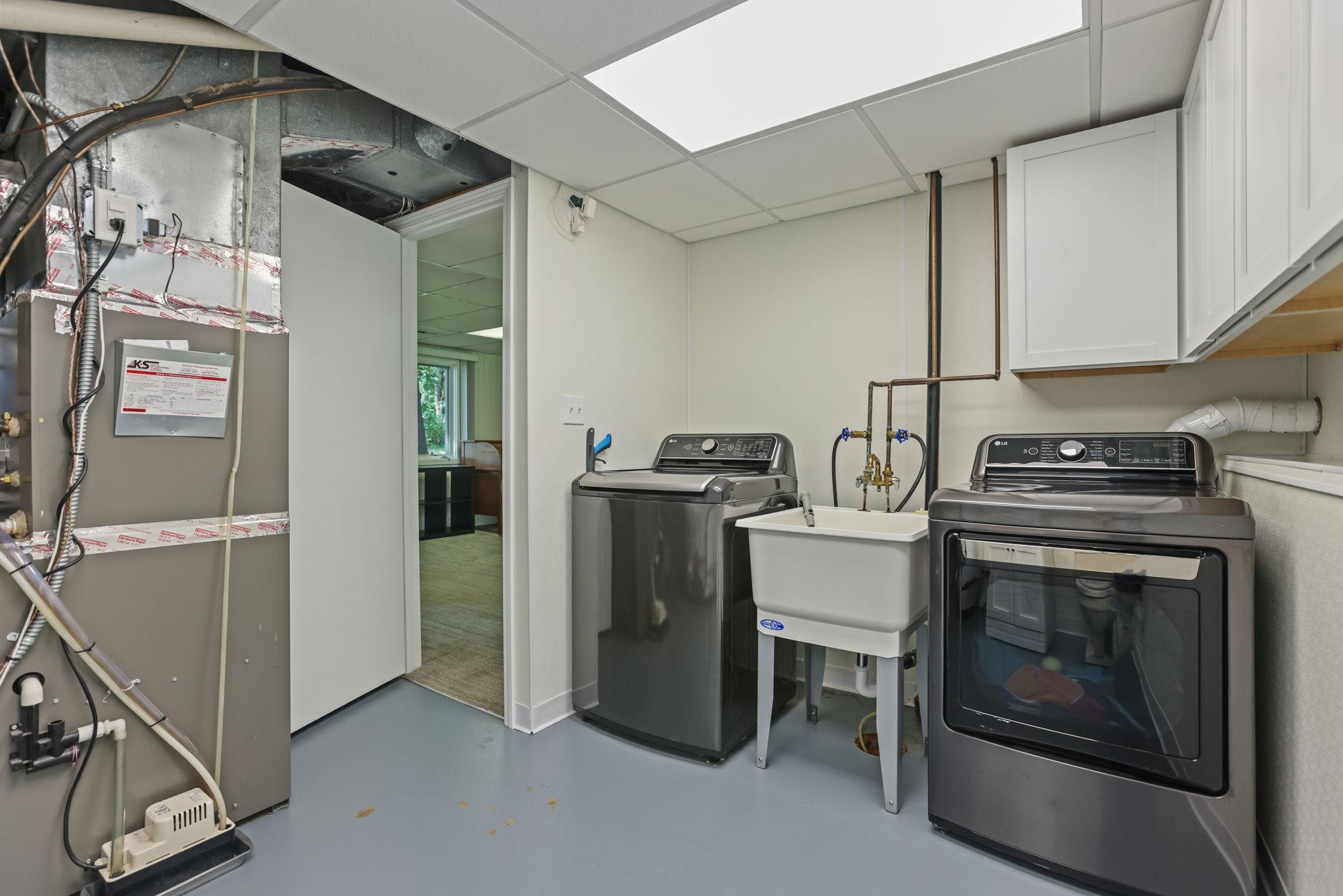 Utility room complete with furnace, water heater, washer, electric dryer and half bath